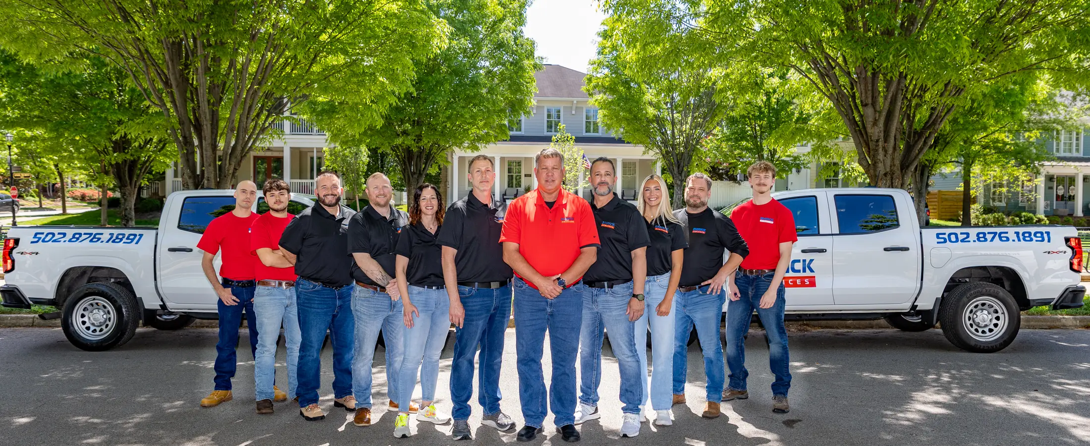 The Emrick Services team standing in front of their branded trucks in Louisville, KY