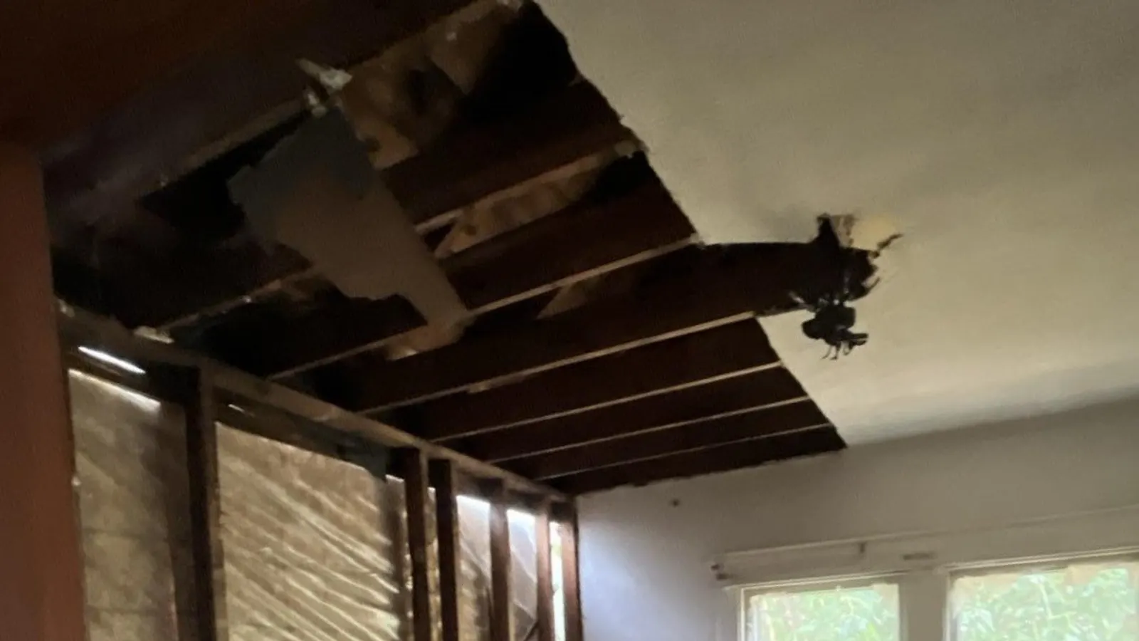 A water-damaged ceiling torn open to the joists in a Louisville home